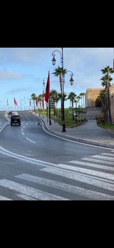 a car driving down a street with palm trees and flags at Chez Housna in Rabat