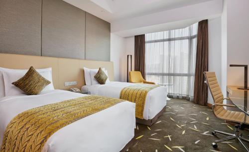 a hotel room with two beds and a desk at Crowne Plaza Zhongshan Wing On City by IHG in Zhongshan