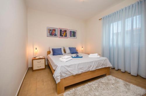 a bedroom with a bed with blue pillows and a window at Apartments Maris in Tribunj