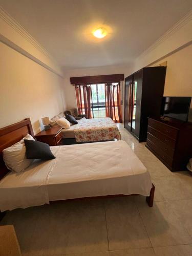 a bedroom with two beds and a flat screen tv at Happyhouse in Algueirão