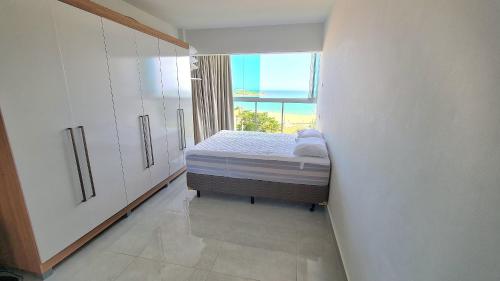 a small bedroom with a bed and a window at Cobertura Duplex Vista Mar Meaipe in Guarapari