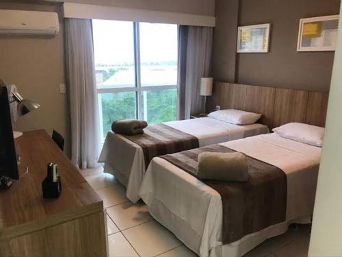 um quarto de hotel com duas camas e uma janela em Rio Stay Barra Hotel no Rio de Janeiro