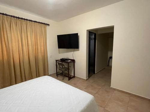 a bedroom with a bed and a flat screen tv at Apartahotel Alvear in Santo Domingo
