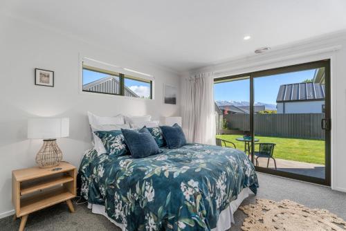 a bedroom with a bed and a sliding glass door at Alpha'N'est - Cromwell Holiday Home in Cromwell