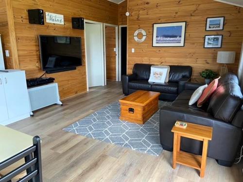 een woonkamer met een bank en een tv bij Relax Cabin - Waihi Beach Holiday Home in Waihi Beach