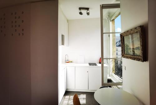 uma pequena cozinha com armários brancos e uma janela em Studio Fontaine Des Innocents em Paris