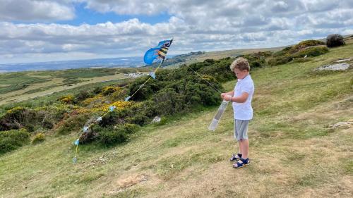 a young boy flying a kite on a hill at Rustic Fawn Lodge with Hot Tub for 4 - Resort Spa in Devon in Chudleigh
