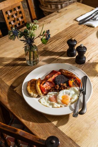 a plate of breakfast food on a wooden table at The Three Horseshoes in Burford