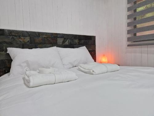 Dos toallas en una cama blanca con una vela. en Ecos del Manantial, en Villarrica