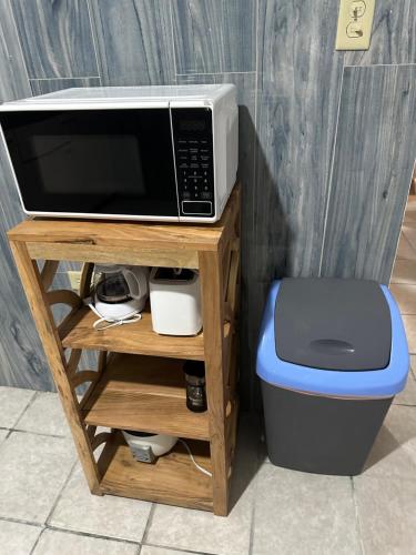 a microwave sitting on a table next to a trash can at Tropicoco Pool House Steps From The Beach in Puerto Nuevo