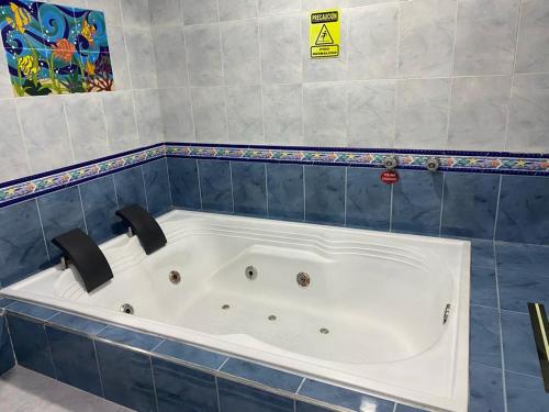 a large bath tub in a blue tiled bathroom at Hotel Yolima Real in Bogotá