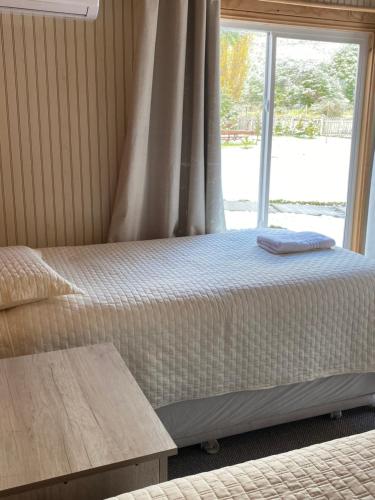 a bedroom with two beds and a window at Baño Privado, Desayuno, Calefacción, 1 Persona in Villa Cerro Castillo