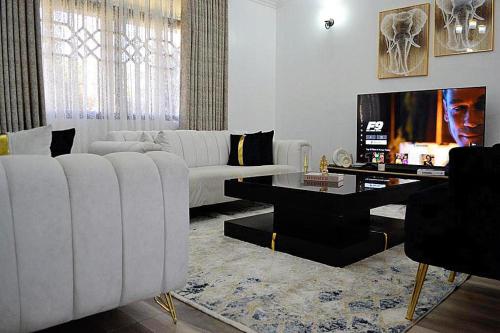 a living room with a white couch and a tv at 3 BDR Luxurious Villa in Milimani Kisumu in Kisumu