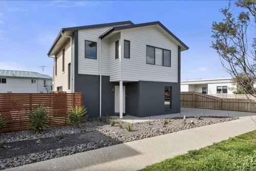 a white house with a fence in front of it at Glas - Seaside Gem in Apollo Bay