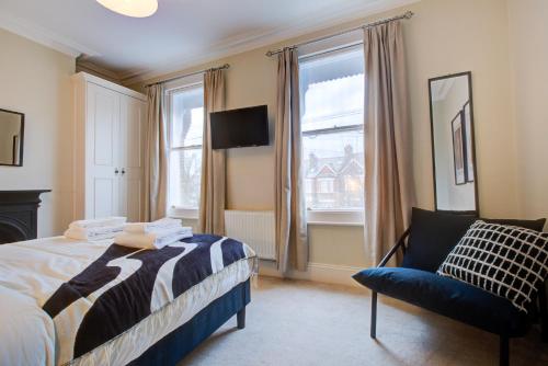 1 dormitorio con 1 cama, 1 silla y 1 ventana en 4 Bedroom, large house, with private parking and just 23 minute train ride to Waterloo en Raynes Park