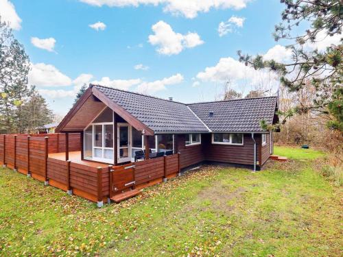 a small house with a large deck in a yard at 8 person holiday home in Rødby-By Traum in Rødby