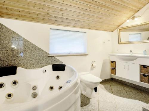 a bathroom with a tub and a toilet and a sink at Holiday Home Klintevej II in Rødby