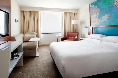 um quarto de hotel com uma cama grande e uma cadeira em Raleigh Marriott Crabtree Valley em Raleigh