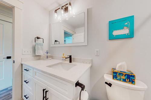 a white bathroom with a sink and a toilet at Of Course You Can in Holden Beach