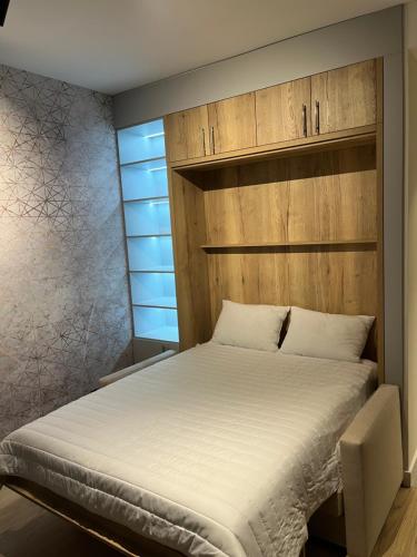 a bedroom with a bed with a wooden headboard at BW Lux Apartments in Sajmište