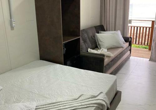 a bedroom with a bed and a couch and a balcony at Pousada São Miguel Beach Beira Mar in Penha