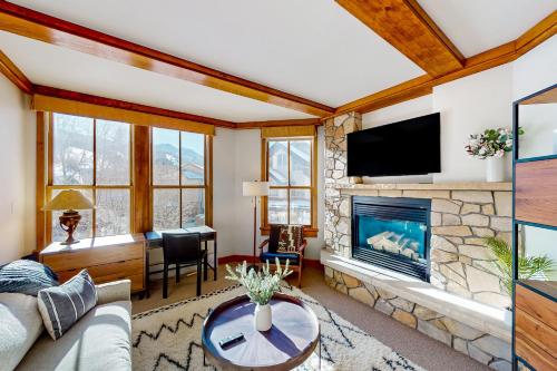 a living room with a stone fireplace and a tv at Palmyra 4E in Telluride