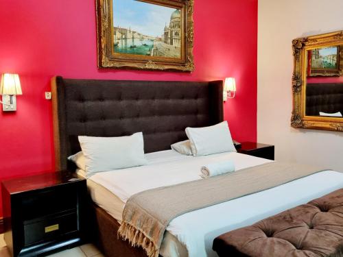a bedroom with a large bed with red walls at Red Apple Guest House in Pretoria