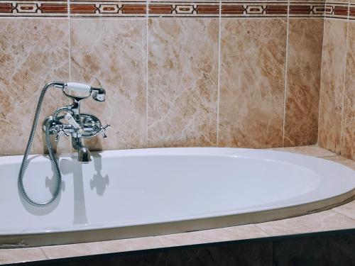 a white bath tub with a shower in a bathroom at Red Apple Guest House in Pretoria