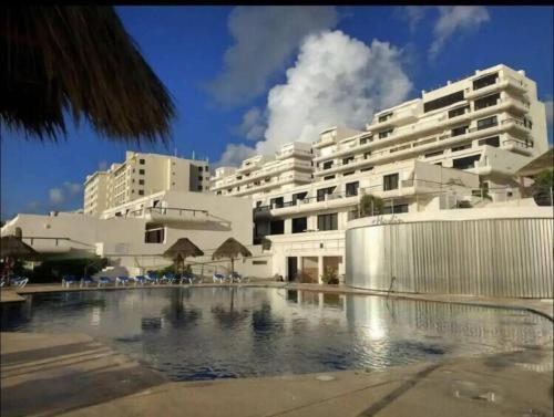 un hotel con piscina frente a un edificio en Amazing beachfront apartment, en Cancún