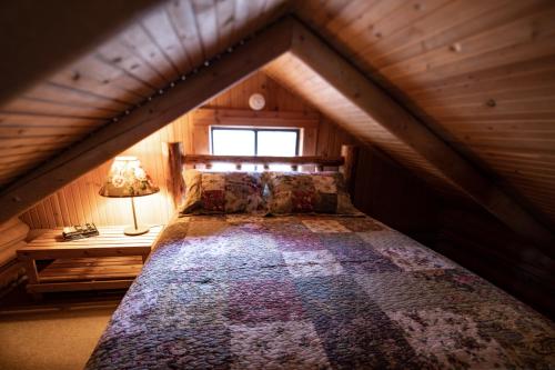 a bed in a wooden room with a window at Experience Montana Cabins - Wildflower #3 in Bigfork