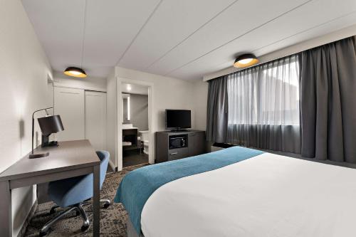 a hotel room with a bed and a desk and a television at Best Western Parkway Hotel Toronto North in Richmond Hill