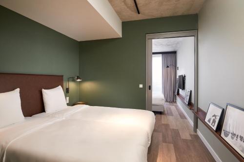 a bedroom with a large white bed and green walls at Corendon Apartments Amsterdam Schiphol Airport in Badhoevedorp