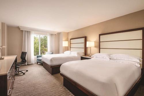 a hotel room with two beds and a desk at Hilton Naples in Naples