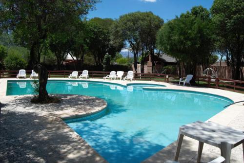 una piscina con sillas y un banco junto a ella en Complejo Arco Iris en Villa Cura Brochero