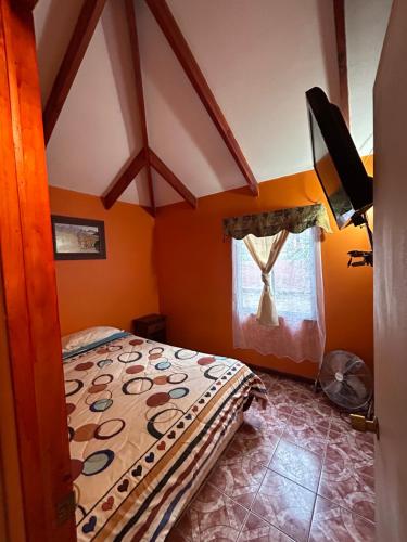 1 dormitorio con paredes de color naranja y 1 cama en una habitación en CABAÑAS RINCON CHILENO, en Monte Grande