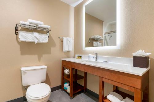 a bathroom with a toilet and a sink with a mirror at Best Western Plus Bend North in Bend