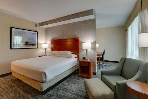 Habitación de hotel con cama y silla en Drury Inn & Suites Independence Kansas City, en Blue Springs