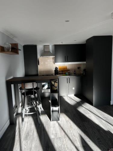 eine Küche mit schwarzen Schränken sowie einem Tisch und Stühlen in der Unterkunft Beautifully Refurbished 1BD Flat - West Kensington in London
