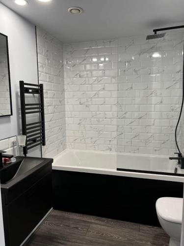 ein Badezimmer mit einer Badewanne, einem WC und einem Waschbecken in der Unterkunft Beautifully Refurbished 1BD Flat - West Kensington in London