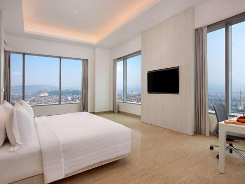 a bedroom with a bed and a desk with a television at Grand Mercure Lampung in Bandar Lampung