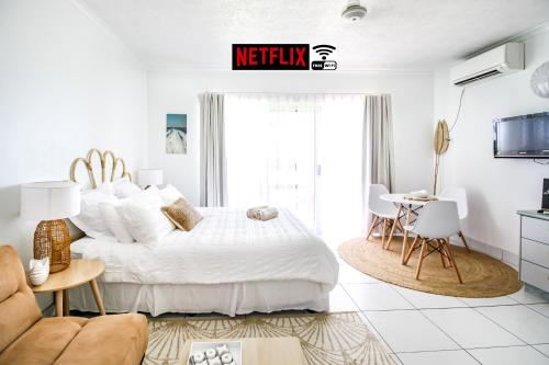 a white bedroom with a bed and a table at WhitsunStays - The Resort by the Sea in Mackay