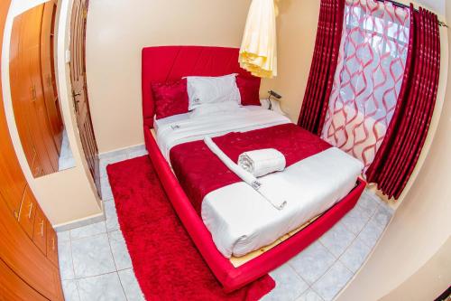 a red bed with a phone sitting on top of it at A&B Cozy Apartments Kitale in Kitale