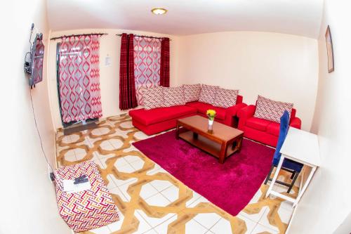 a living room with a red couch and a table at A&B Cozy Apartments Kitale in Kitale