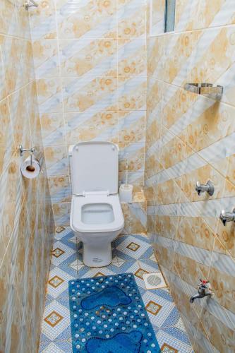 a bathroom with a white toilet and a blue rug at A&B Cozy Apartments Kitale in Kitale