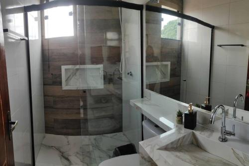 a bathroom with two sinks and a glass shower at Casa Nova no Centro de Penedo in Penedo