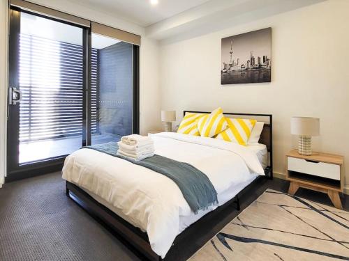 1 dormitorio con cama grande y ventana grande en Modern Elegance: 2 Bedroom Oasis w/ Free Parking, en Epping