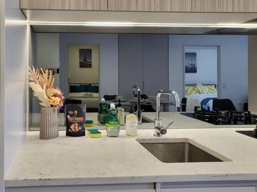 a kitchen counter with a sink and a living room at Modern Elegance: 2 Bedroom Oasis w/ Free Parking in Epping