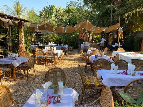 eine Gruppe von Tischen und Stühlen mit weißem Tischtuch in der Unterkunft MANGO LODGE in Bubaque