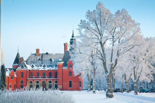 a large red building with a tree in the snow at Lejondals Slott in Bro