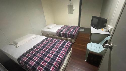 um pequeno quarto com duas camas e uma televisão em HOTEL 59 em Sibu